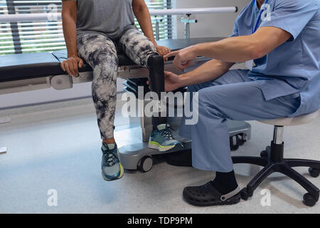 Physiothérapeute mâle prothèse de jambe de réglage de female patient in hospital Banque D'Images