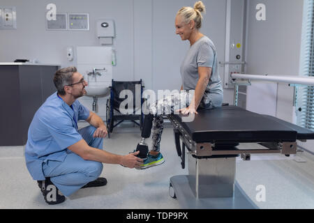 Physiothérapeute mâle prothèse de jambe de réglage de female patient in hospital Banque D'Images