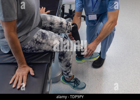 Physiothérapeute mâle prothèse de jambe de réglage de female patient in hospital Banque D'Images