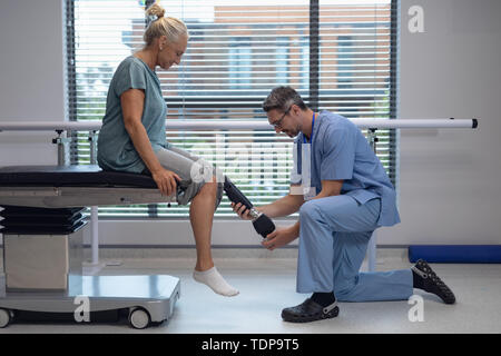 Physiothérapeute mâle prothèse de jambe de réglage de female patient in hospital Banque D'Images