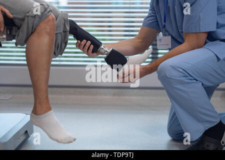 Physiothérapeute mâle prothèse de jambe de réglage de female patient in hospital Banque D'Images