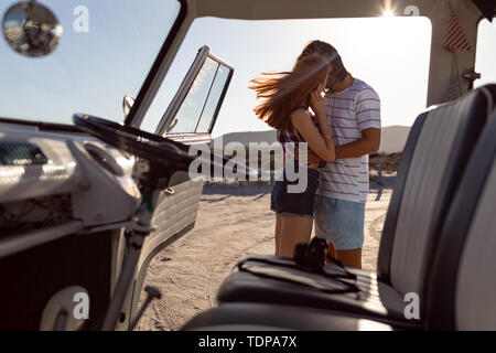 Jeune couple qui s'embrassent près de camping-van at beach Banque D'Images