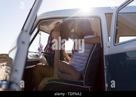 Jeune couple qui s'embrassent sur le siège avant de camper van at beach Banque D'Images