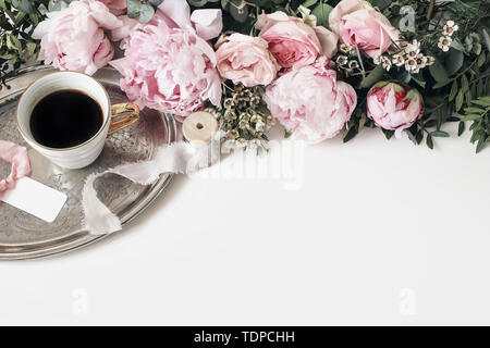 Mariage ou anniversaire féminin composition table avec Garland, rose, roses, pivoines, fleurs de cire et de feuilles vertes. Tasse de café, étiquettes cadeaux et s Banque D'Images