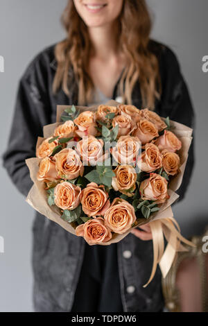 Couleur café cappuccino, fleurs roses à l'eucalyptus. Petit magnifiques bouquets dans femme la main. Boutique de fleurs concept. Livraison de fleurs Banque D'Images