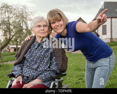 Jeune femme avec grand-mère en fauteuil roulant Banque D'Images