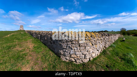 Vieux mur de pierres sèches le long d'une pelouse avec une tour ronde dans la distance ; à South Shields, Tyne and Wear, England Banque D'Images