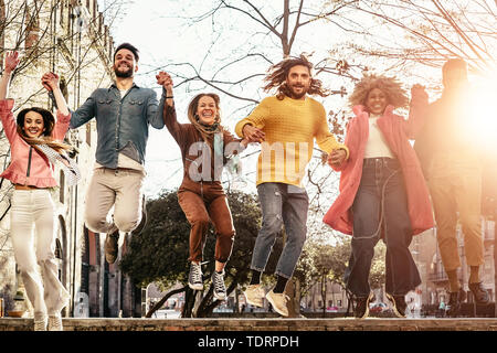 Groupe d'amis heureux de sauter en plein air - jeunes millénaire s'amuser danser et célébrer au coucher du soleil à l'extérieur Banque D'Images