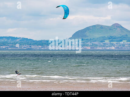 Longniddry Bents, Firth of Forth, Ecosse, Royaume-Uni, le 18 juin 2019. UK : météo kite surfeurs ont des conditions idéales à marée basse avec un fort vent et soleil dans le Firth of Forth saccadée vers l'horizon distinctif d'Édimbourg sur la baie Banque D'Images