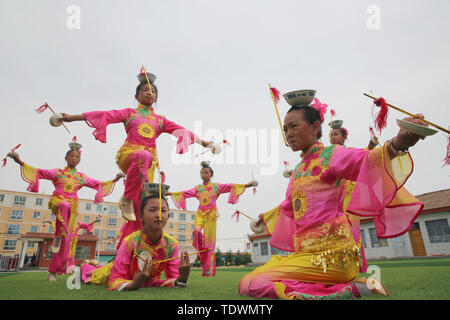 Le Gansu, du Gansu, en Chine. 20 Juin, 2019. Le Gansu, Chine - 20 juin 2019 : l'héritière du patrimoine culturel immatériel est instruire les enfants à effectuer l'héritage non génétiques sur programme de danse pagode bol sur l'aire d'embarquement de l'école primaire minle minle county, zhangye ville, province de Gansu.Minleding pagode de danse folklorique bol allie l'acrobatie avec la danse, qui reflète une sorte de danse composé, réalisé et apprécié par les anciens soldats et civils, à l'aide de bols de riz comme accessoires et matériaux locaux dans leur travail. Credit : ZUMA Press, Inc./Alamy Live News Banque D'Images