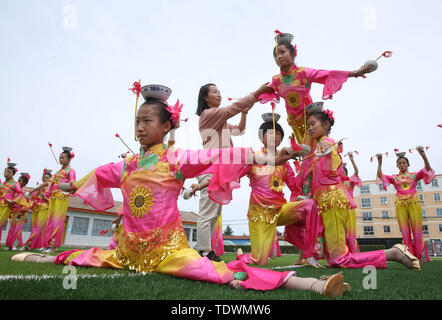 Le Gansu, du Gansu, en Chine. 20 Juin, 2019. Le Gansu, Chine - 20 juin 2019 : l'héritière du patrimoine culturel immatériel est instruire les enfants à effectuer l'héritage non génétiques sur programme de danse pagode bol sur l'aire d'embarquement de l'école primaire minle minle county, zhangye ville, province de Gansu.Minleding pagode de danse folklorique bol allie l'acrobatie avec la danse, qui reflète une sorte de danse composé, réalisé et apprécié par les anciens soldats et civils, à l'aide de bols de riz comme accessoires et matériaux locaux dans leur travail. Credit : ZUMA Press, Inc./Alamy Live News Banque D'Images