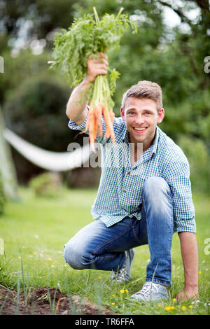 Homme avec un bunsh de carottes fraîchement récolté à partir du propre jardin, Allemagne Banque D'Images