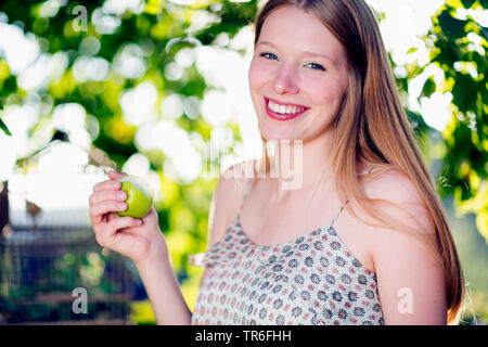 Jeune femme mangeant une pomme verte, Allemagne Banque D'Images