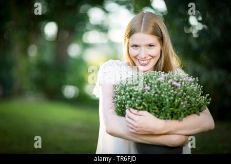 Jeune femme blonde avec un aster dans le bras , Allemagne Banque D'Images