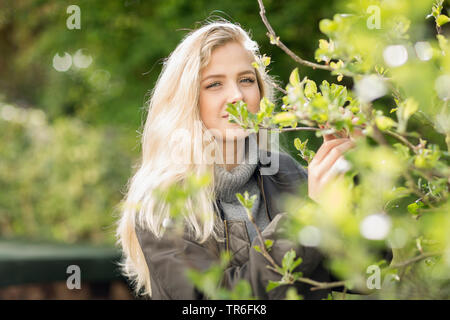 Jeune femme blonde dans un apple tree, Allemagne Banque D'Images