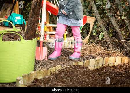 Petite fille aux bottes en caoutchouc rose jardinage, Allemagne Banque D'Images