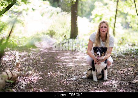 Berger Australien (Canis lupus f. familiaris), mettent bas avec une jeune femme sur un chemin forestier, Allemagne Banque D'Images