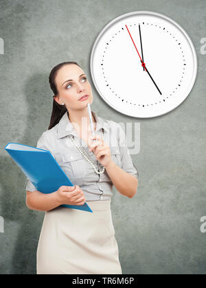 Méditer businesswoman standing avec un dossier de fichiers en face d'une horloge, Allemagne Banque D'Images