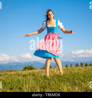 Jeune femme en dirndl dansant sur une prairie de montagne, l'Allemagne, la Bavière Banque D'Images