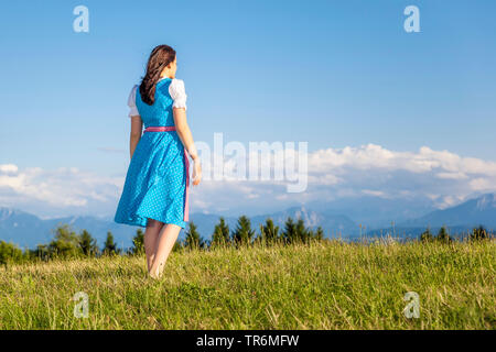 Jeune femme en dirndl debout sur une prairie de montagne, l'Allemagne, la Bavière Banque D'Images