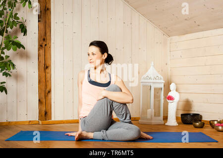 Woman practicing yoga sur un tapis de yoga à la télévision, Allemagne Banque D'Images