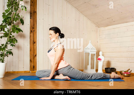 Woman practicing yoga sur un tapis de yoga à la télévision, Allemagne Banque D'Images