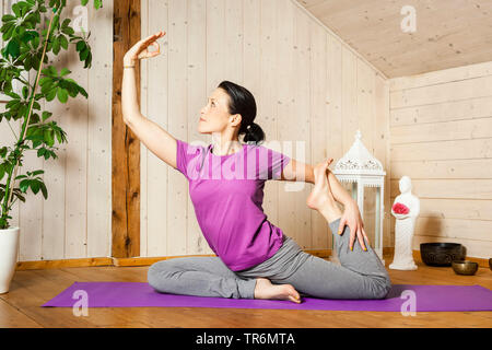 Woman practicing yoga sur un tapis de yoga à la télévision, Allemagne Banque D'Images