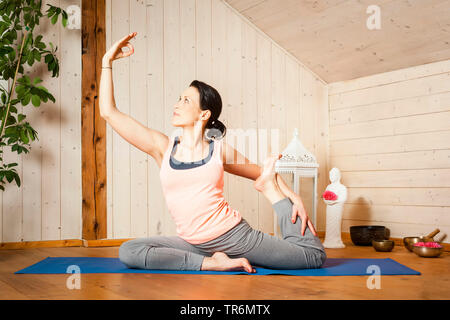 Woman practicing yoga sur un tapis de yoga à la télévision, Allemagne Banque D'Images