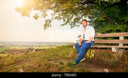 L'homme musclé dans la nature, assis sur un banc en bois, Allemagne Banque D'Images