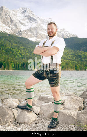 Nice bon à l'homme en costume traditionnel bavarois debout au bord du lac Eibsee de la Zugspitze, dans l'arrière-plan, l'Allemagne, la Bavière Banque D'Images