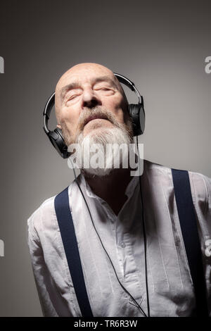 Personnes âgées bald head man écouter de la musique avec des écouteurs, Allemagne Banque D'Images