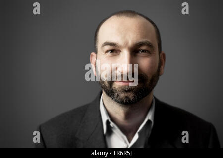 Portrait d'un homme sympathique avec barbe en face de fond gris, Allemagne Banque D'Images