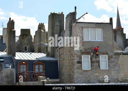 Rappeling maçon d'un toit et de plâtrage une façade de la vieille ville, France, Bretagne, Saint-Malo Banque D'Images