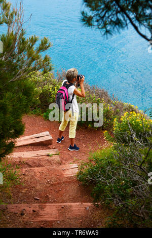 woman standing on footpath along the coast and taking photos, France, Provence, Sanary-sur-Mer Banque D'Images