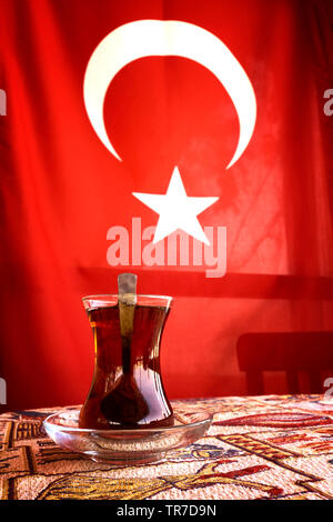 Du thé turc (cay) servi dans la tasse de thé, ou en verre en forme de tulipe, avec drapeau turc dans l'arrière-plan. Banque D'Images