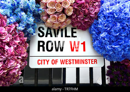 Londres, Angleterre, Royaume-Uni. Savile Row street sign entouré de fleurs artificail Banque D'Images