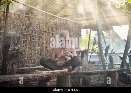 La vie Asie vieux grand-père oncle travaillant dans accueil / homme sérieux âgés vivant dans la campagne de la vie des populations rurales dans la Thaïlande bambou tissage bask Banque D'Images