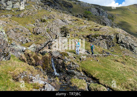 Deux marcheurs faire leur chemin jusqu'à Dovedale Crag colombe avec la crête d'Hartsop Comment ci-dessus de l'horizon, Lake District, Cumbria, Royaume-Uni Banque D'Images