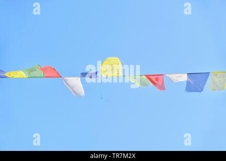 Drapeaux de prière Tibetains colorés isolés contre le ciel bleu Banque D'Images