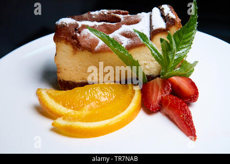 Cheesecake aux fraises et les tranches d'orange sur une assiette blanche. Banque D'Images