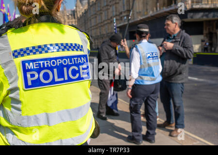 Officier de police au premier plan, montre en tant qu'officier de liaison de police traite avec quelques manifestants au mois de mars pour quitter le rallye dans le centre de Londres. Banque D'Images