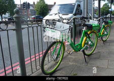 Une paire de chaux dockless ebikes parqué par le chalkers au carrefour dans le sud-ouest de Londres, en Angleterre, avec €1 pour démarrer affiche devant le panier Banque D'Images