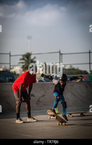 Un enfant coachés tout en planche à roulettes dans un skatepark à Bangalore, Inde. Banque D'Images