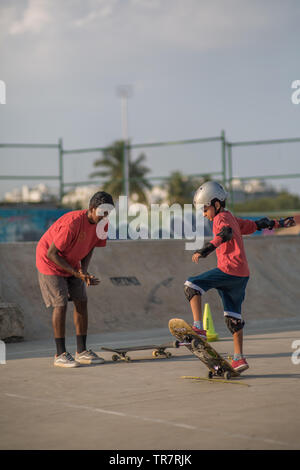 Un enfant coachés tout en planche à roulettes dans un skatepark à Bangalore, Inde. Banque D'Images