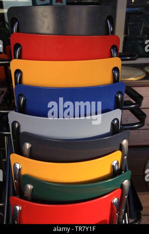 Chaises multicolores entassés en face d'un restaurant Banque D'Images