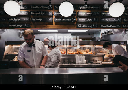 Wells-next-the-Sea, Royaume-Uni - 20 Avril 2019 : Le personnel servant du poisson et des frites à l'intérieur du poisson et le français populaire chip shop dans les puits-prochain-la-mer, dans une ville balnéaire Banque D'Images