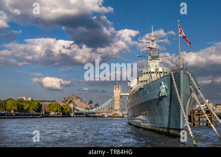 Le HMS Belfast navire battant Union Jack Flag, amarré sur la Tamise en fin d'après-midi au soleil, avec le Tower Bridge et le Tower Hôtel derrière Londres SE1 Banque D'Images