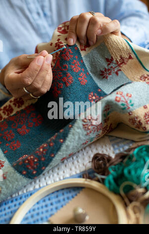 Close Up of Senior Woman broderie d'assise à la maison Banque D'Images