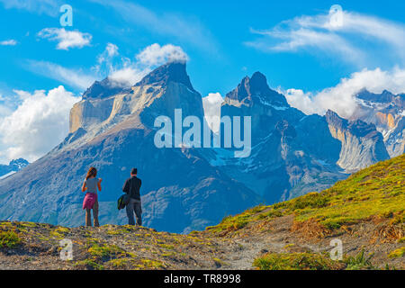 Deux touristes, une femme et un homme, par les sommets des Andes de Cuernos del Paine au coucher du soleil, parc national Torres del Paine, Puerto Natales, en Patagonie, au Chili. Banque D'Images