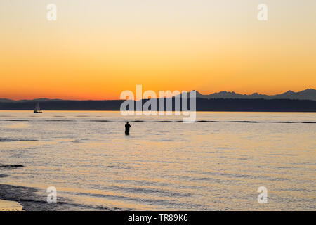 La pêche est un pêcheur Golden Gardens Park, Seattle, Washington au cours d'un magnifique coucher de soleil Banque D'Images